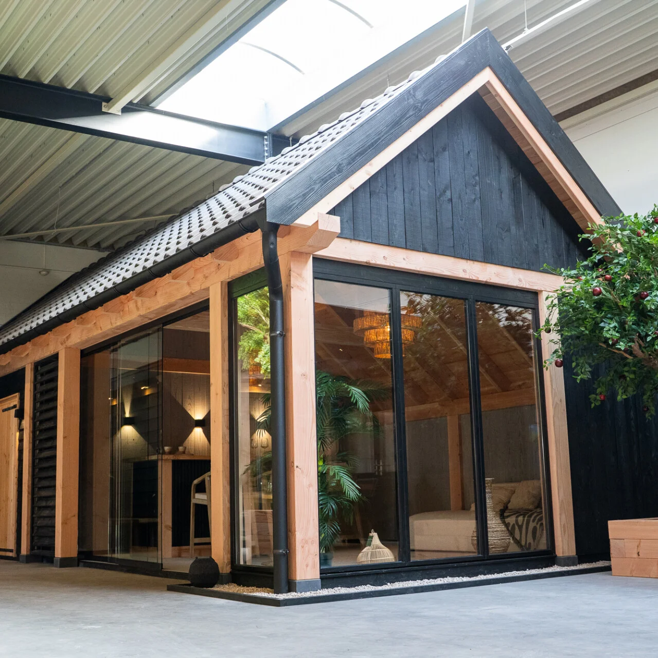 Buitenverblijf met zwarte gevelbekleding, douglas kozijnen en glazen schuifwanden in de showroom